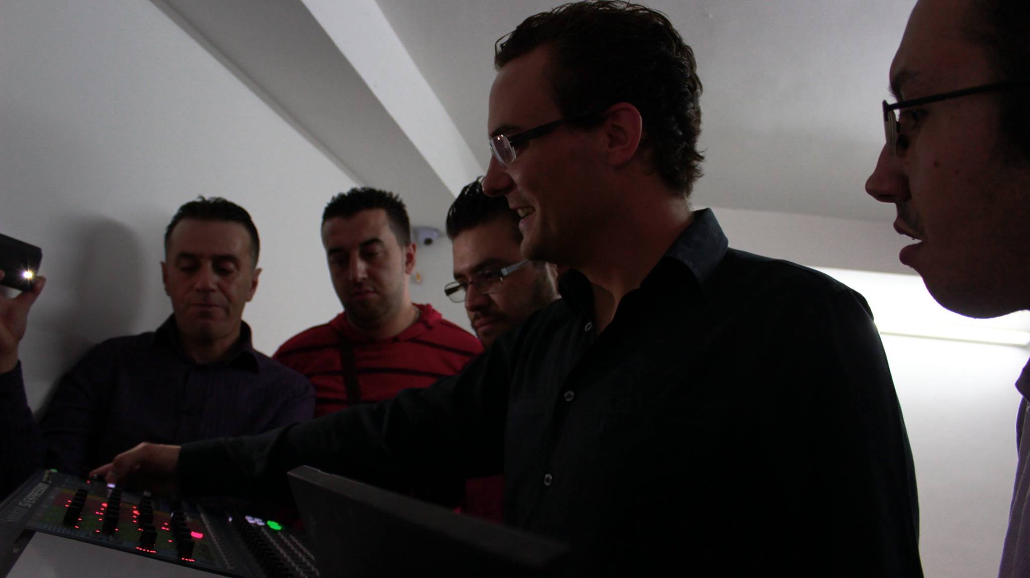 Sam instructing a group around a professional audio mixing console