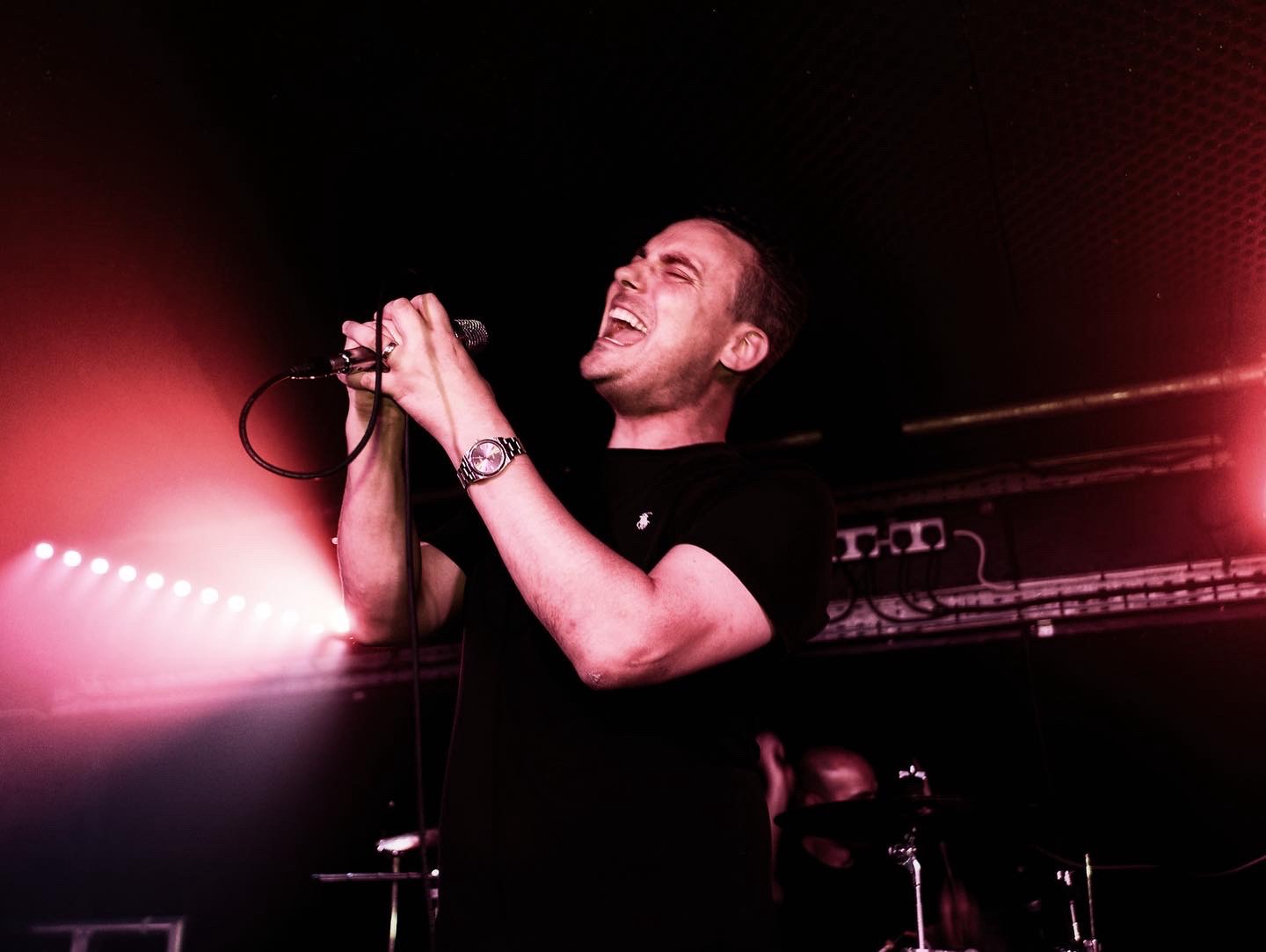 Sam singing on a stage with red lights